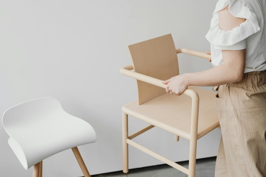A woman arranging modern minimalist chairs in a stylish, indoor setting.