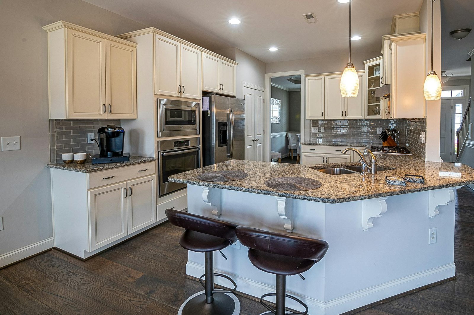 Spacious modern kitchen featuring a granite island and stainless steel appliances.